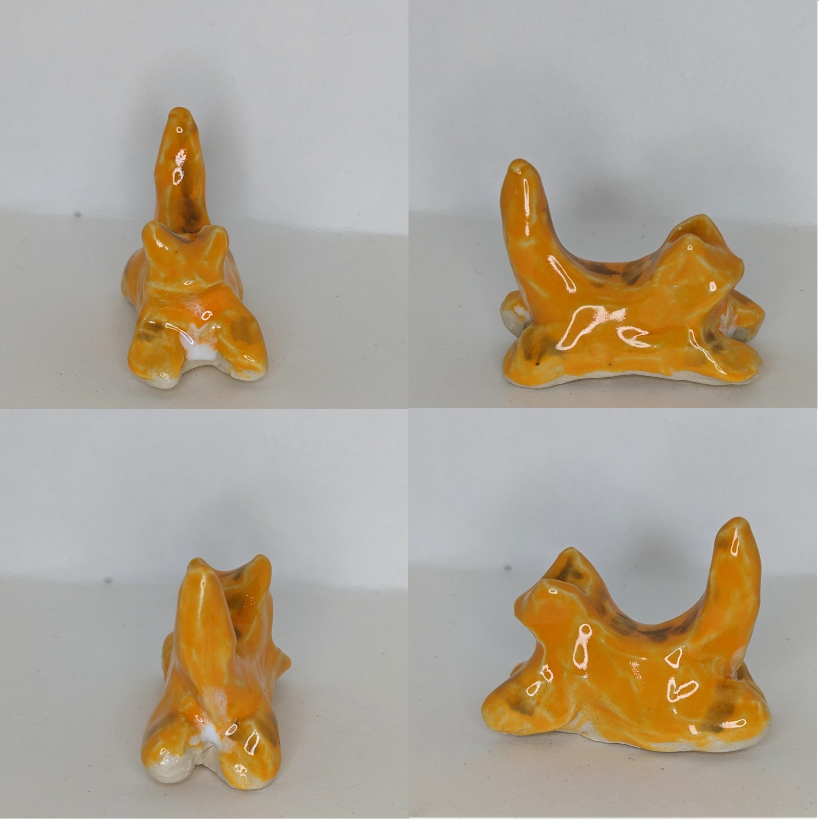 4 views of a small orange ceramic cat in a splayed out position. It has striping.